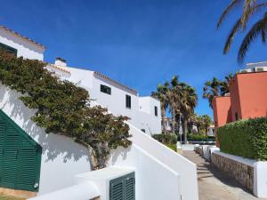 un edificio blanco con una puerta verde y palmeras en Lujo en Menorca, Ciutadella, piscina, padel, aparcamiento, en Sa Caleta