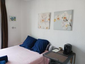 Un dormitorio con una cama con almohadas azules y una mesa. en studio à 2 mn à pied de la plage en Niza