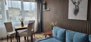 ein Wohnzimmer mit einem Tisch und einem blauen Sofa in der Unterkunft VILLA NORTH Apartament in Jastrzębia Góra