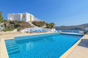 a blue swimming pool with blue chairs and a house at Mykonos Citadel in Mikonos