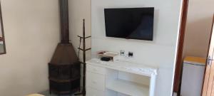 a living room with a tv on a wall at Casa Moreira´s Chalés in Monte Verde
