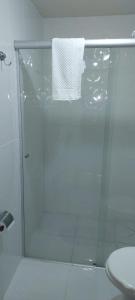 a bathroom with a glass shower with a toilet and a towel at Casa Moreira´s Chalés in Monte Verde