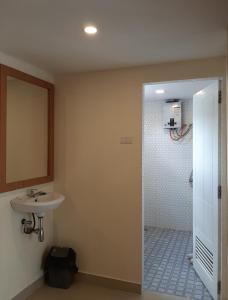 uma casa de banho com um lavatório, um espelho e um chuveiro em BERYL HOMESTAY em Tarutung