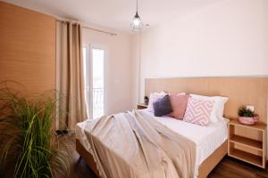 a bedroom with a bed with pink and purple pillows at Villy Suites in Argasi