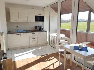 a kitchen with white cabinets and a table and chairs at Fewo 18 im Strandhaus Lobbe mit Balkon in Lobbe