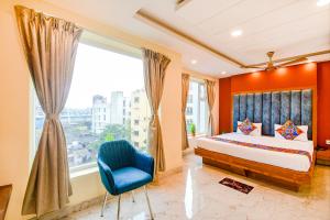 a bedroom with a bed and a blue chair and a window at FabHotel Aqua Tulip in Kolkata