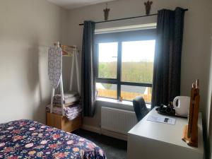 a bedroom with a bed and a window and a desk at Room with a view in Newry