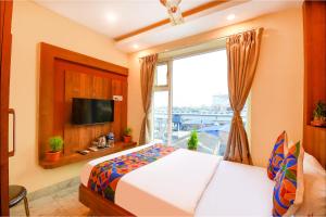 a bedroom with a bed and a large window at FabHotel Aqua Tulip in Kolkata