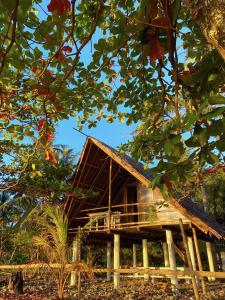 una casa con tetto di paglia tra gli alberi di Kasa Raya By The Sea a Tibiao