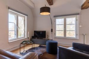salon z kanapą i telewizorem oraz 2 oknami w obiekcie Dachstuv von Esmarch w mieście Tönning