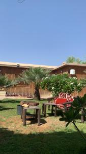 una mesa de picnic y bancos en un patio en استراحة وشاليه الكوخ, en Unaizah
