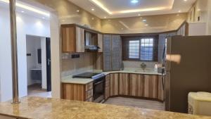a kitchen with wooden cabinets and a refrigerator at استراحة وشاليه الكوخ in Unayzah