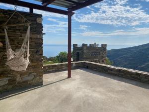 a porch with a hammock on the side of a building at Andros Vineyard house with sea view in Sinétion