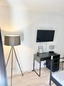 een kamer met een bureau, een televisie en een lamp bij City Loft in Toplage Mainz-Kastel in Wiesbaden