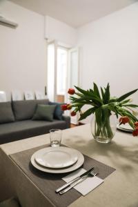 a table with a plate and a vase of flowers on it at Aura Home rent of rooms with shared kitchen in Bari