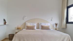 a white bedroom with a large bed with two pillows at Desert Call in Arad