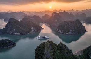 a cruise ship in the middle of a river with mountains at Elite of the Seas in Ha Long