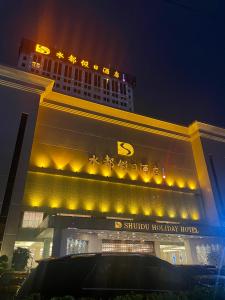 een gebouw met gele lichten er 's nachts op bij Shenzhen Shuidu Holiday Hotel, North Railway Station in Shenzhen