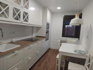 a kitchen with white cabinets and a sink and a table at Agradable adosado en soto de llanera in Llanera