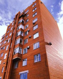 a tall red brick building with white windows at Апартаменты в новом ЖК in Pavlodar