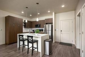 a kitchen with a island with two chairs and a refrigerator at Modern 1B Downtown SLC with WFH Setup, Gym, Fast Wi-Fi, Pool in Salt Lake City