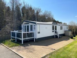 a white mobile home with a porch and a yard at Cragside View Lodge in Newton on the Moor