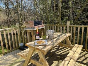 a wooden picnic table with a bottle of wine and a pizza at Cragside View Lodge in Newton on the Moor