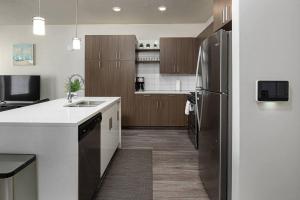 a kitchen with a stainless steel refrigerator and wooden cabinets at Modern 1B Downtown SLC with WFH Setup, Gym, Fast Wi-Fi, Pool in Salt Lake City