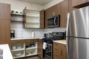 a kitchen with wooden cabinets and a stainless steel refrigerator at Modern 1B Downtown SLC with WFH Setup, Gym, Fast Wi-Fi, Pool in Salt Lake City
