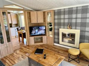 a living room with a fireplace and a tv at Cragside View Lodge in Newton on the Moor +16 photos