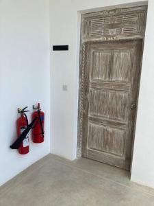 um quarto com dois extintores de incêndio e uma porta de madeira em Ahadi Beachfront Apartment, 2 Bed By YourHost Kanamai em Mombasa