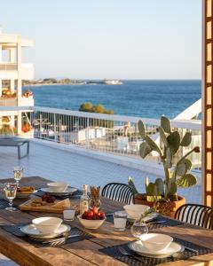 een houten tafel met eten op een balkon met uitzicht op de oceaan bij Sea View Beach Penthouse - Athens Coast in Athene