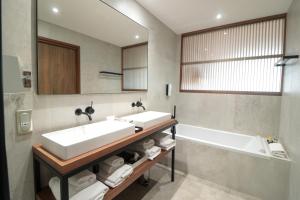 a bathroom with a sink and a tub and a mirror at Golden Tulip Porto-Vecchio in Porto-Vecchio