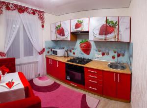 a kitchen with red cabinets and a sink with strawberries on the cabinets at Luxury apartment Sicheslavska street in Kryvyi Rih