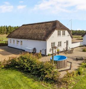 un grand bâtiment blanc avec un toit de chaume dans l'établissement Lildgaard, à Frøstrup