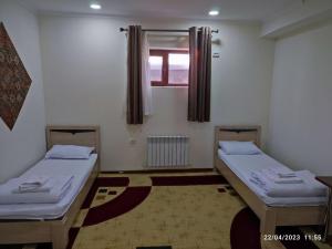 two twin beds in a room with a window at Donish Hotel in Bukhara
