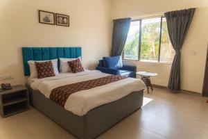 1 dormitorio con 1 cama, 1 silla y 1 ventana en Girivihar Pure Veg Resort Lonavala - ગિરિવિહાર રિસોર્ટ ,, en Lonavala