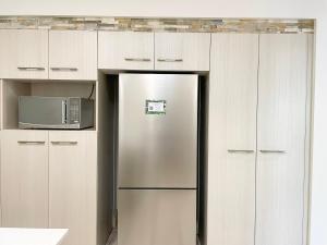 a stainless steel refrigerator in a kitchen with white cabinets at Trinity Links Resort in Cairns