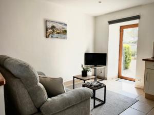 a living room with a couch and a tv at Le Domaine du Ganquis in Belz