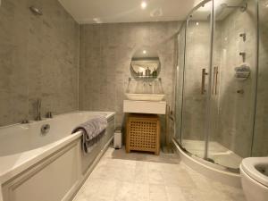 a bathroom with a tub and a sink and a shower at Award Winning 2023 luxury Holiday Rental Apartment Stratford London in London