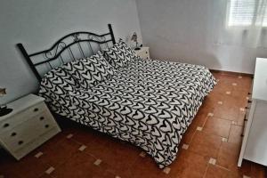 um quarto com uma cama com um edredão preto e branco em Casa Lucas em Vejer de la Frontera