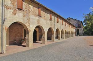a large brick building with arches on a street at Antica Grancia Benedettina in Colorno