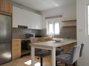 una cucina con tavolo, 2 sedie e frigorifero di Zoe’s House a Città di Kos