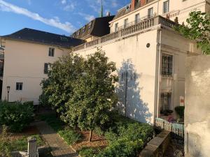 uma árvore em frente a um edifício branco em Initial by balladins, hôtel Broisin em Aix-les-Bains