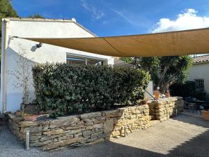 a building with a stone wall and an umbrella at Le Bastidon in Sanary-sur-Mer
