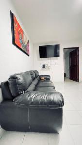 a black leather couch in a living room with a tv at Cómodo y muy relajante alojamiento a 5 minutos de la playa in Acapulco