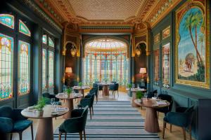 une salle à manger avec des tables, des chaises et des vitraux dans l'établissement Château Hôtel Grand Barrail, à Saint-Émilion