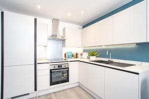 een witte keuken met witte kasten en een wastafel bij Hemel Apartments- Elite Escape in Hemel Hempstead