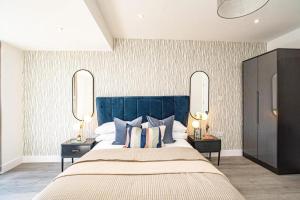 a bedroom with a large bed with pillows and mirrors at Hemel Apartments- Elite Escape in Hemel Hempstead