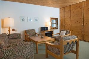 ein Wohnzimmer mit einem Sofa, Stühlen und einem Tisch in der Unterkunft Ferienwohnung Schweizerhof 604 Lenzerheide in Lenzerheide